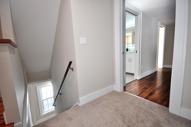 staircase with carpet floors, baseboards, and wood finished floors