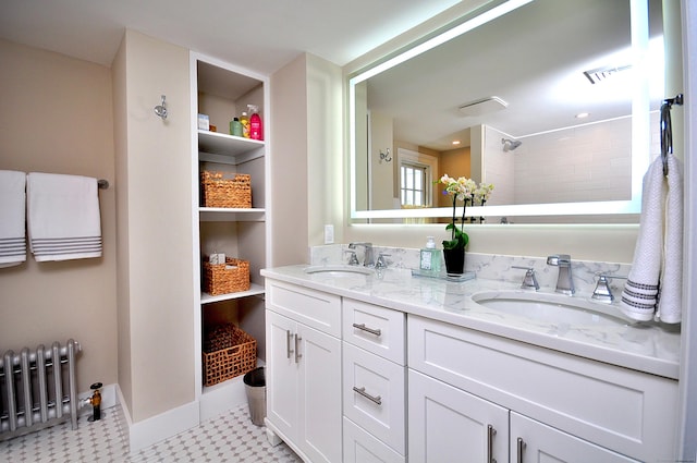 full bath featuring a tile shower, double vanity, a sink, and radiator