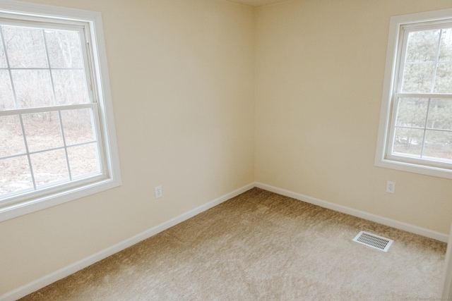 carpeted empty room with plenty of natural light, visible vents, and baseboards