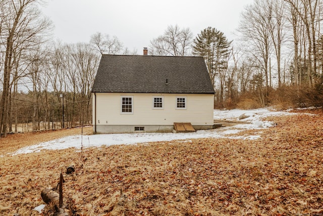 snow covered house with roof with shingles and a chimney