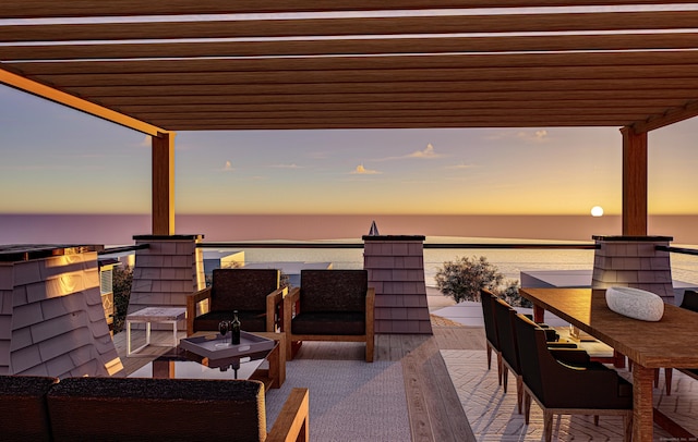 patio terrace at dusk with an outdoor hangout area, a balcony, and a water view