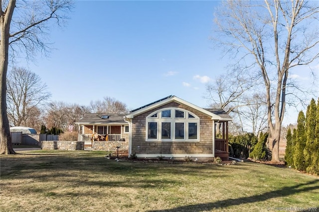 back of house featuring covered porch, a lawn, and fence