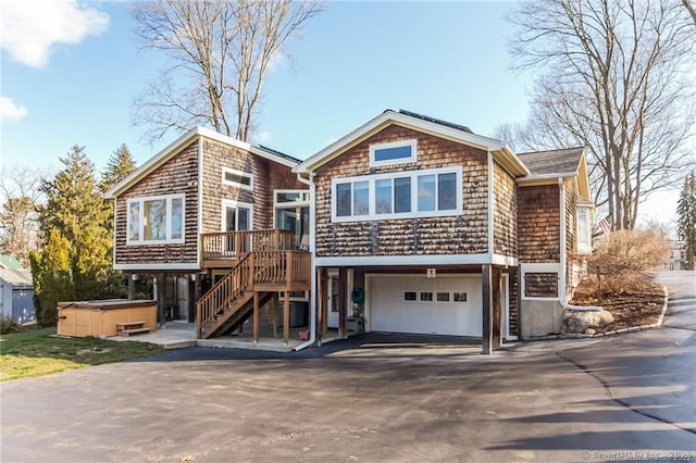 view of front of home with driveway, stairway, an attached garage, and a hot tub