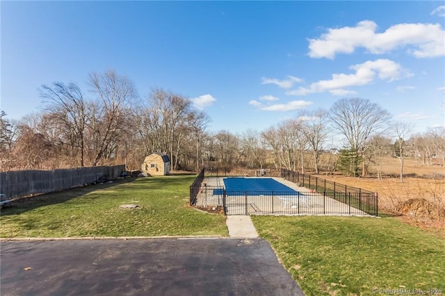 view of pool with a fenced in pool, a fenced backyard, an outbuilding, a storage unit, and a yard