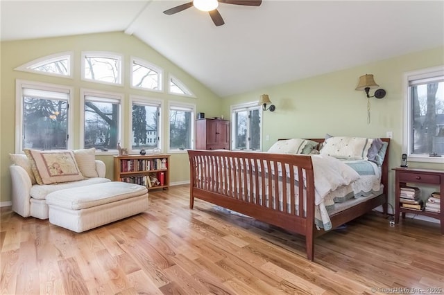 bedroom with a ceiling fan, multiple windows, vaulted ceiling, and light wood-style flooring