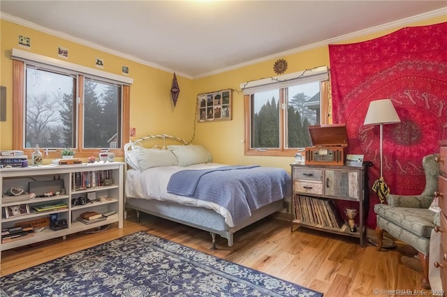 bedroom with ornamental molding and wood finished floors