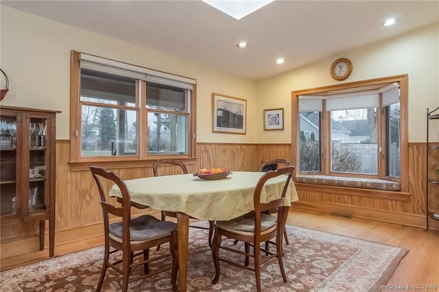 dining space featuring recessed lighting, a wainscoted wall, wood walls, and wood finished floors