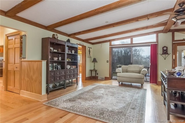 living room featuring beam ceiling, baseboards, and wood finished floors