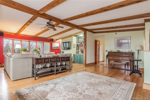 living area with vaulted ceiling with beams, wood finished floors, a ceiling fan, and baseboards