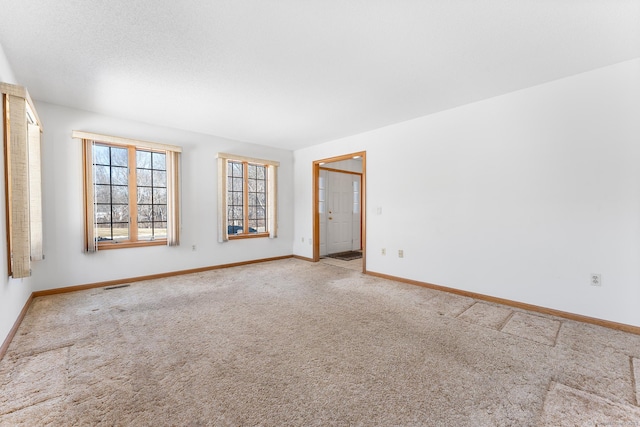 carpeted empty room featuring a textured ceiling and baseboards