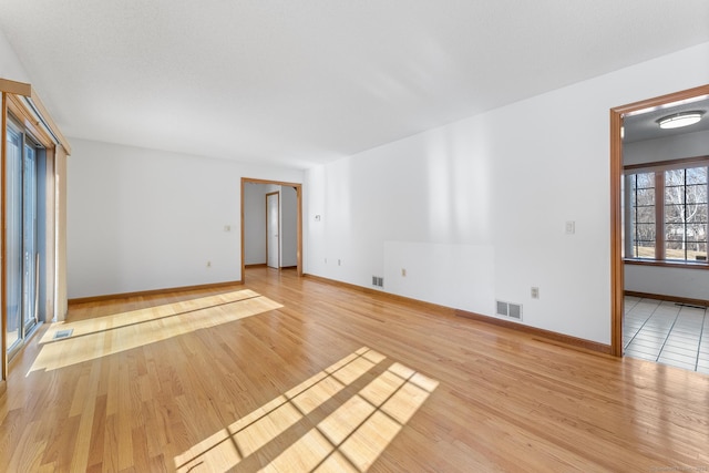 empty room featuring visible vents, light wood-style flooring, and baseboards