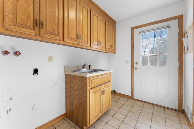 clothes washing area featuring cabinet space, baseboards, a sink, and light tile patterned flooring