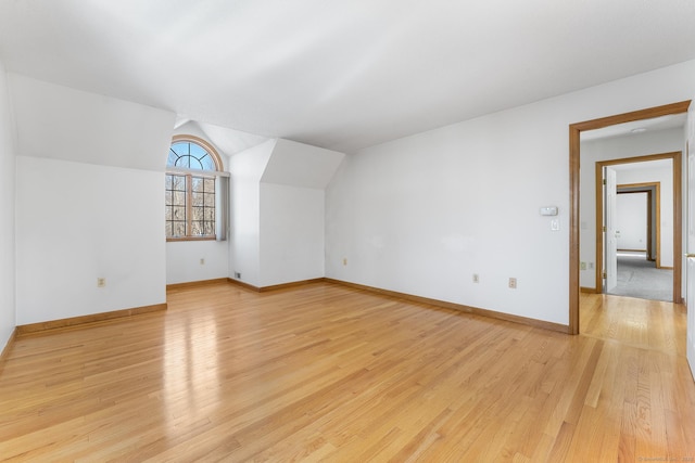 bonus room featuring vaulted ceiling, light wood-style flooring, and baseboards