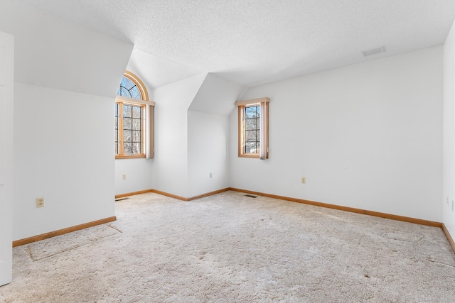 bonus room with a textured ceiling, visible vents, baseboards, vaulted ceiling, and carpet