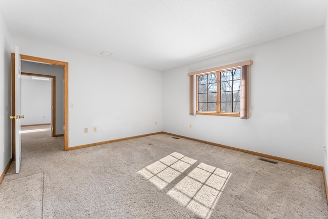 spare room with carpet, visible vents, and baseboards