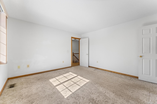 carpeted spare room featuring baseboards and visible vents