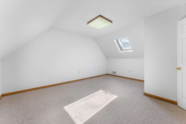 additional living space with vaulted ceiling with skylight, baseboards, visible vents, and carpet flooring