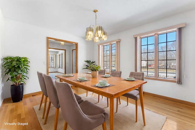 dining space with light wood finished floors, a notable chandelier, and a wealth of natural light