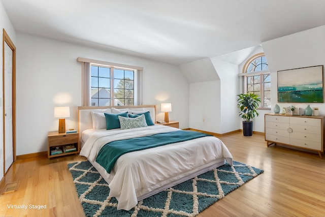 bedroom with lofted ceiling, wood finished floors, and baseboards