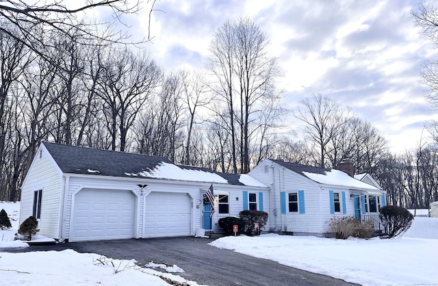 ranch-style home with a garage, driveway, a chimney, and a shingled roof