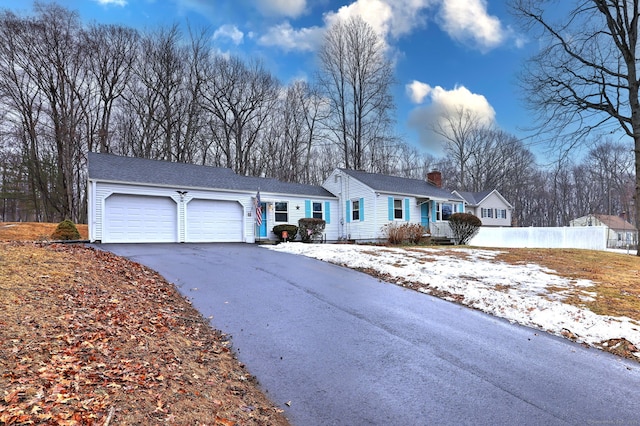 single story home featuring aphalt driveway, a chimney, an attached garage, and fence