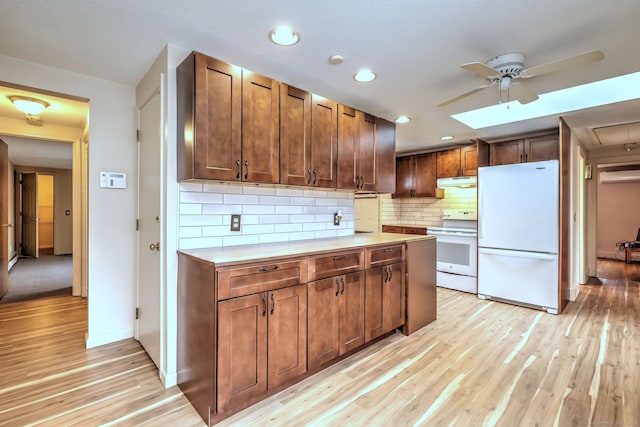 kitchen with light countertops, light wood-style flooring, backsplash, white appliances, and under cabinet range hood