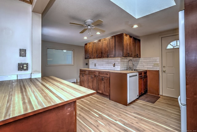 kitchen featuring decorative backsplash, dishwasher, light wood-style flooring, light countertops, and a sink