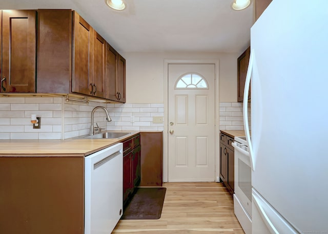 kitchen with light wood finished floors, light countertops, white appliances, and a sink