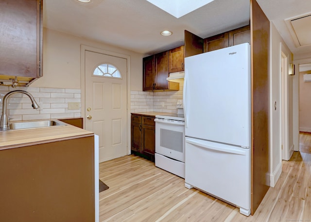 kitchen featuring tasteful backsplash, light wood-type flooring, white appliances, and a sink