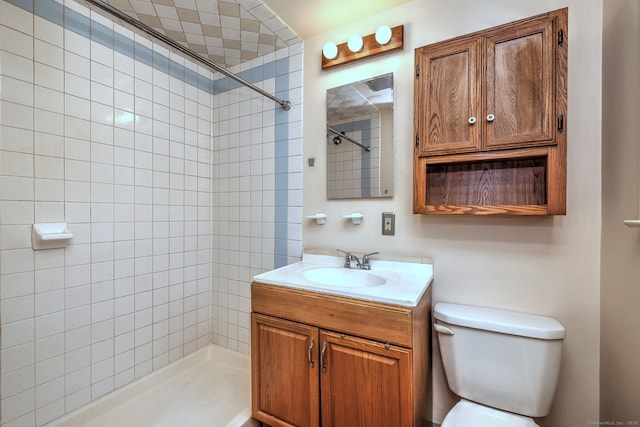 bathroom featuring tiled shower, vanity, and toilet