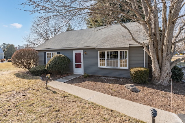 ranch-style home with a front yard and roof with shingles