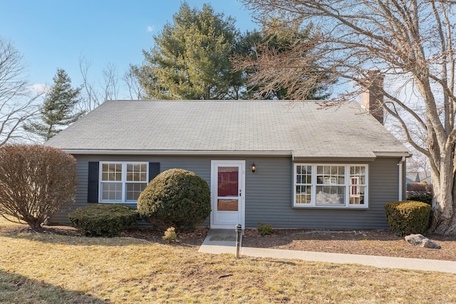 view of front of home with a chimney and a front lawn