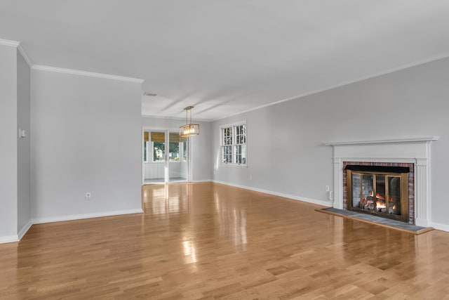 unfurnished living room with light wood-style floors, a fireplace, baseboards, and ornamental molding