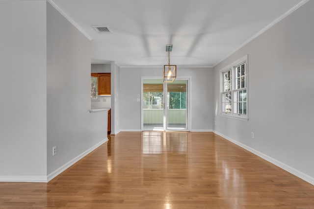 unfurnished dining area with crown molding, light wood-type flooring, visible vents, and baseboards