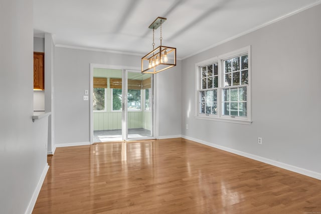 unfurnished dining area featuring light wood-type flooring, a notable chandelier, baseboards, and crown molding