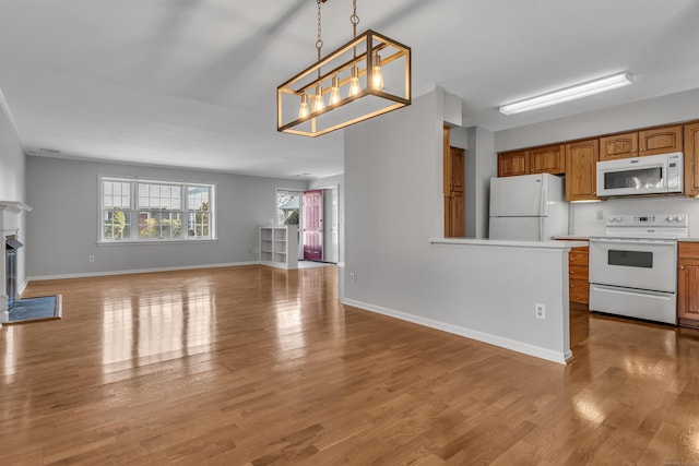 kitchen featuring white appliances, brown cabinets, open floor plan, light countertops, and pendant lighting