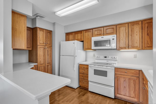 kitchen featuring light countertops, white appliances, light wood-style floors, and brown cabinets