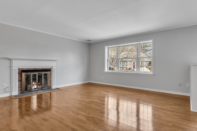 unfurnished living room featuring ornamental molding, a fireplace, and wood finished floors