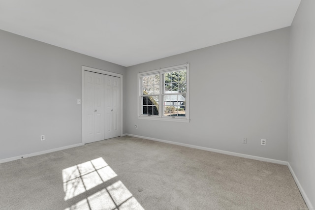 unfurnished bedroom featuring a closet, light carpet, and baseboards