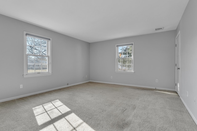 spare room featuring baseboards, visible vents, and light colored carpet