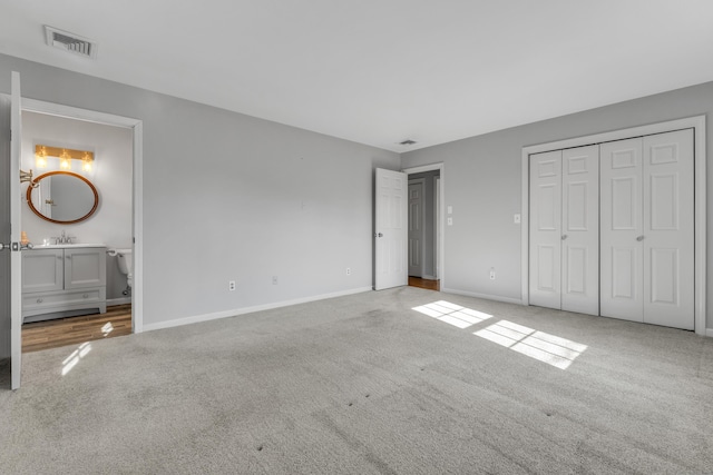 unfurnished bedroom featuring connected bathroom, carpet flooring, visible vents, and baseboards