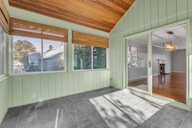 unfurnished sunroom featuring a warm lit fireplace, lofted ceiling, and wood ceiling