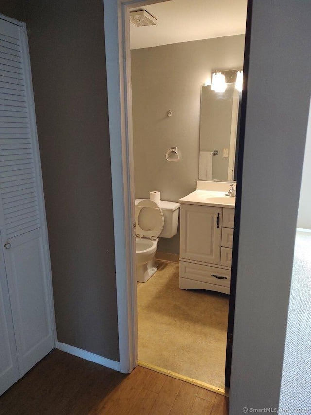 bathroom with visible vents, toilet, wood finished floors, baseboards, and vanity