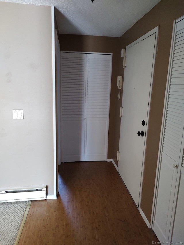 corridor featuring wood finished floors, baseboards, and a baseboard radiator