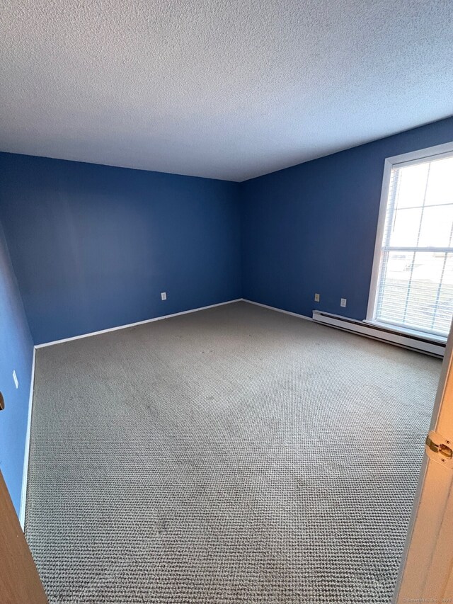 unfurnished room featuring a baseboard heating unit, carpet floors, and a textured ceiling