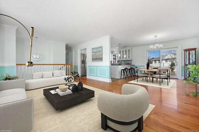 living area featuring a notable chandelier, crown molding, and light wood-style floors