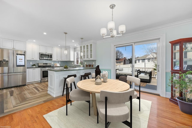 dining area featuring a chandelier, light wood finished floors, recessed lighting, and crown molding