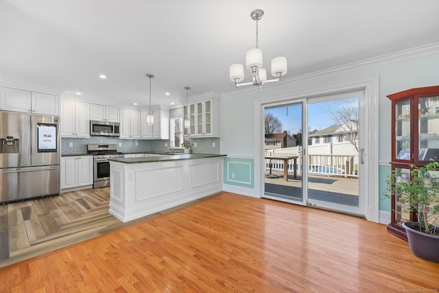 kitchen with tasteful backsplash, dark countertops, a peninsula, stainless steel appliances, and white cabinetry