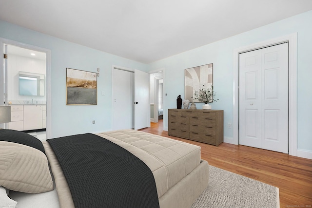 bedroom with connected bathroom, light wood-style flooring, and baseboards