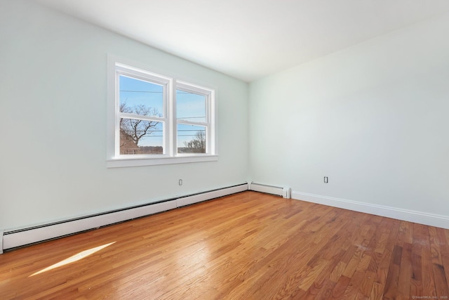 spare room with a baseboard heating unit, light wood-style flooring, and baseboards